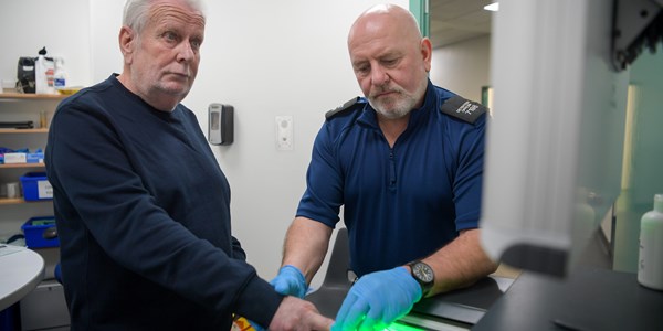 Officer and alleged offender at finger print scanner machine