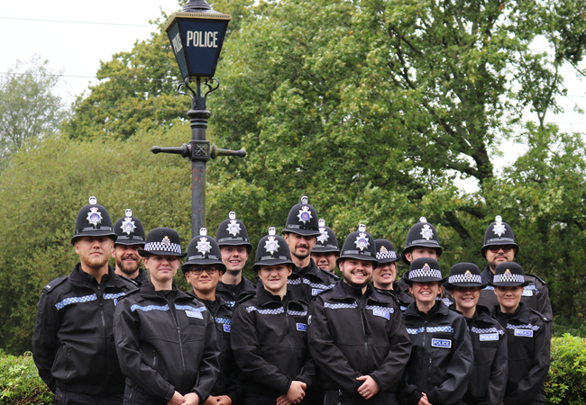 A large group of Police Officers gathered by a police street lamp