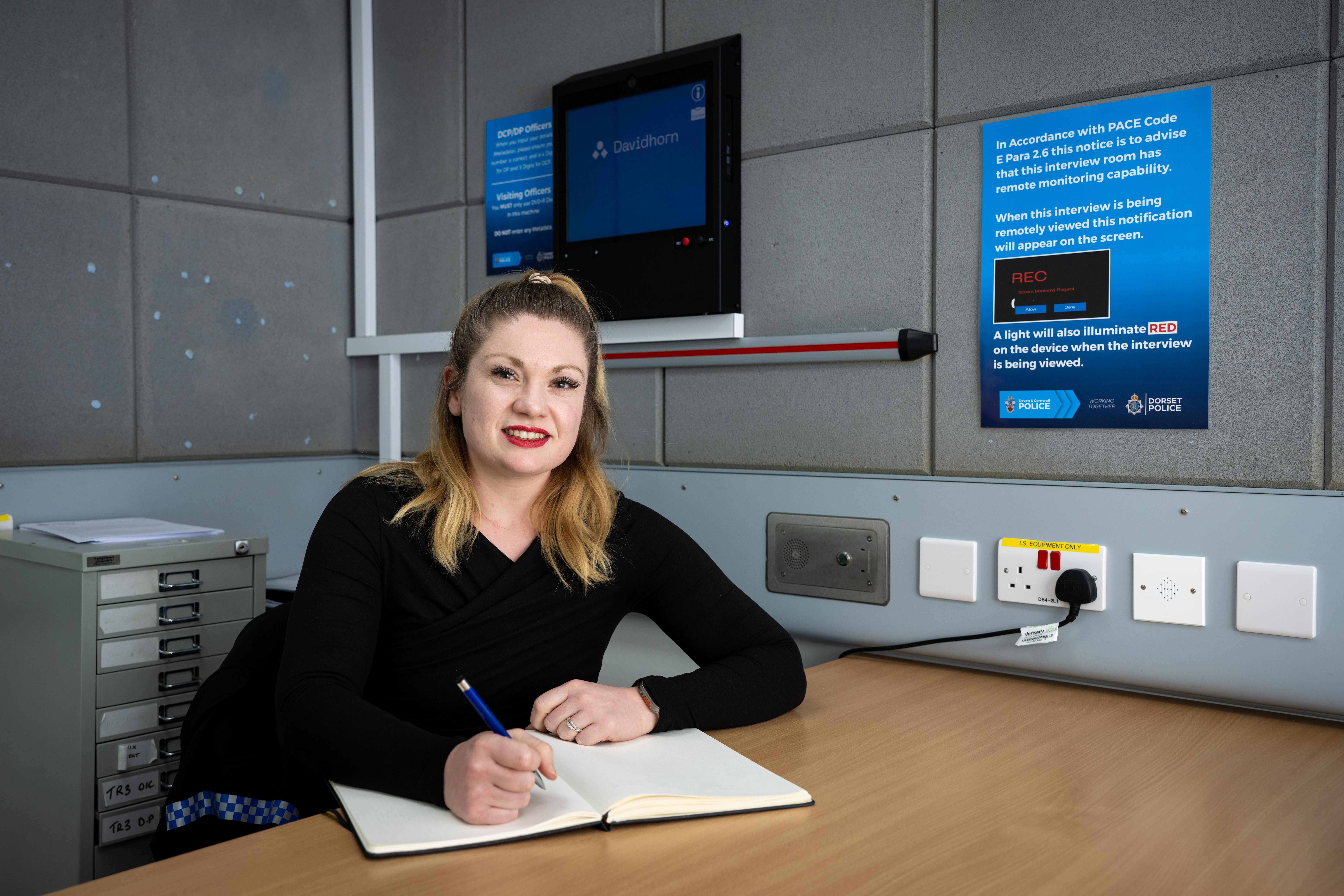 Smiling female police staff member sitting at desk