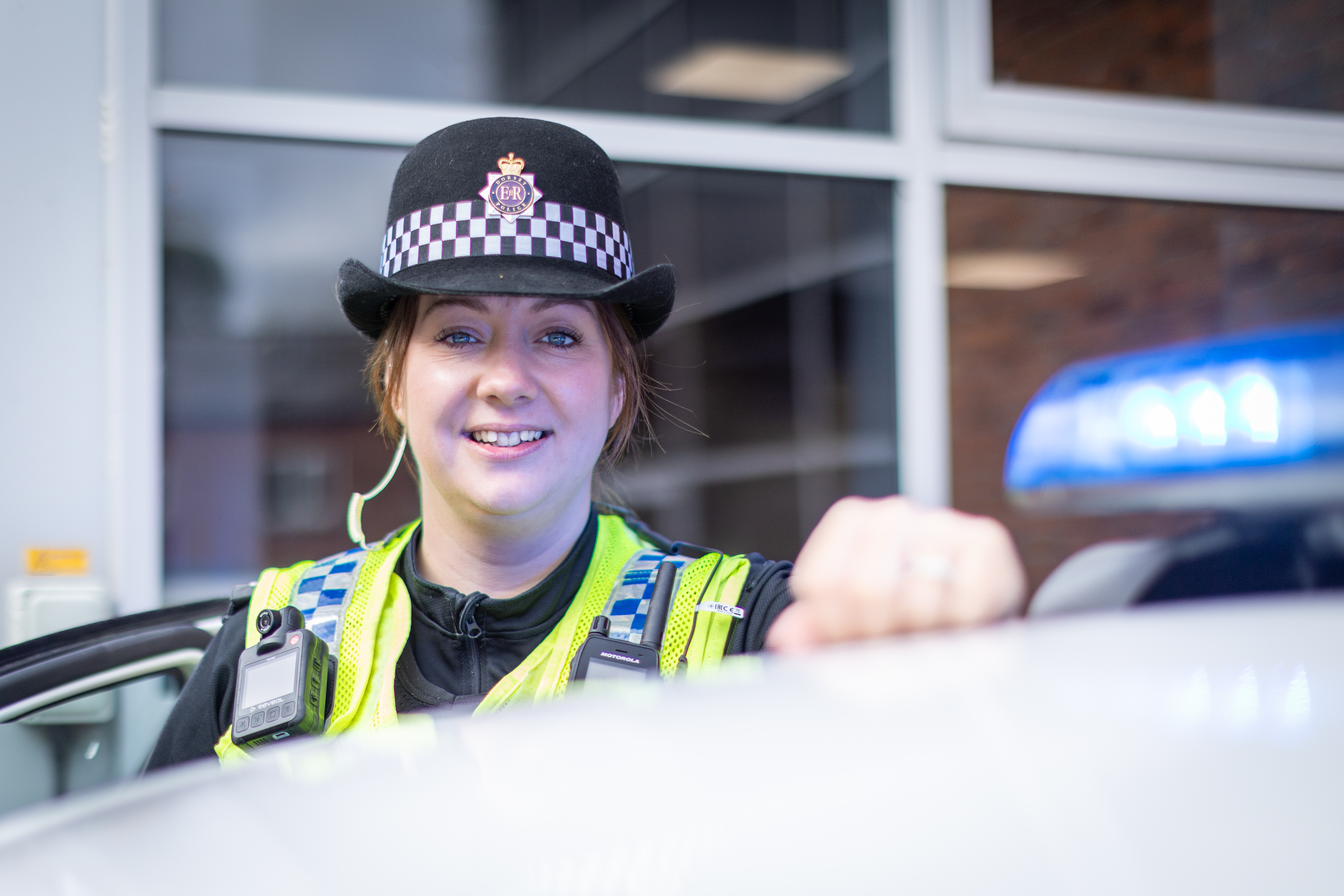 Female sergeant standing behind police car and smiling